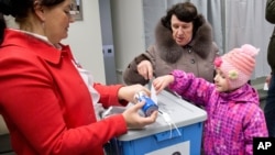 A little girl helps her mother to cast a ballot at a polling station in Tallinn, Estonia, March 1, 2015. 