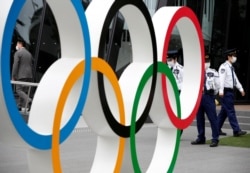 Security personnel stand guard near the Olympic rings monument during a rally by anti-Olympics protesters outside the Japanese Olympic Committee headquarters in Tokyo, Japan, May 18, 2021.