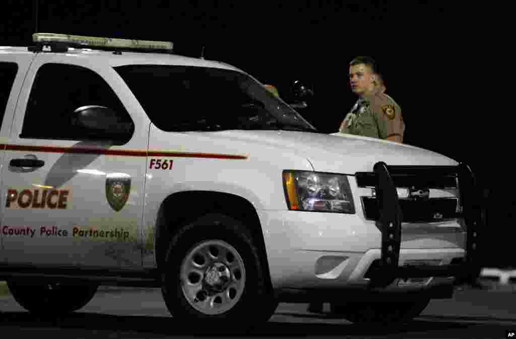 Police watch from the parking lot of the Ferguson Police Department as protesters gather across the street, March 12, 2015.