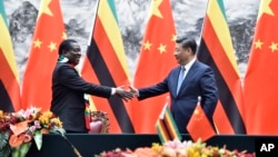 Zimbabwean President Emmerson Mnangagwa, left, shakes hands with Chinese President Xi Jinping as they pose for the media after a signing ceremony at the Great Hall of the People in Beijing, China, April 3, 2018.
