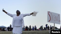 Một phụ nữ cầu nguyện cho các nạn nhân phía sau rạp chiếu phim, nơi nghi can James Holmes xả súng vào khán giả ở Aurora, Colorado