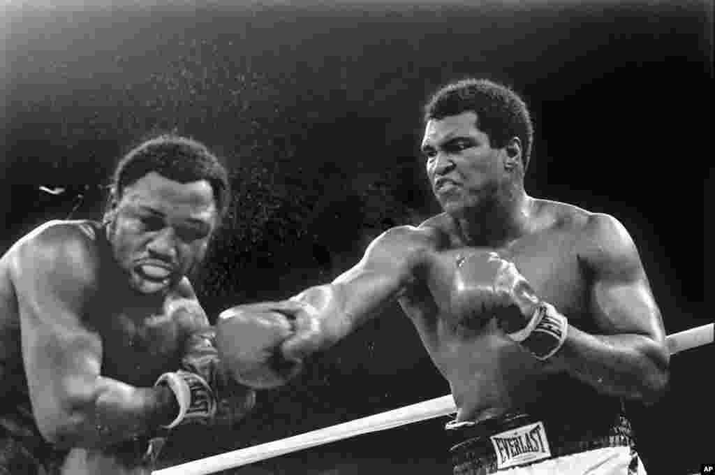 FILE - Spray flies from the head of challenger Joe Frazier as heavyweight champion Muhammad Ali connects with a right in the ninth round of their title fight in Manila, Philippines, Oct. 1, 1974. Ali has died, his family said, June 3, 2016. He was 74. 