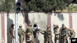 Pasukan keamanan Afghanistan menyelamatkan seorang pria dari kompleks stasiun televisi Shamshad di Kabul pasca serangan, 7 November 2017.