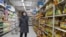 A shopper wearing a face mask browses an aisle of cooking oil in a supermarket in Beijing on March 16, 2020. 