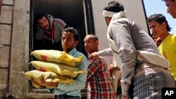 A Yemeni volunteer carries bags of rice to displaced people, who fled fighting in the southern city of Aden, during a food distribution effort in Taiz, Yemen, May 9, 2015.