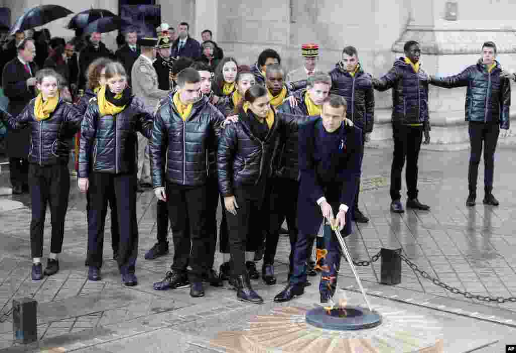 French President Emmanuel Macron lights up the Tomb of the Unknown Soldier under the Arc de Triomphe during ceremonies, Nov. 11, 2018 in Paris.
