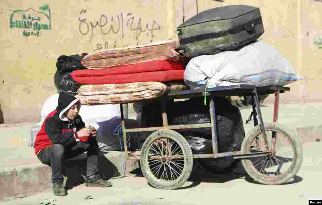 A boy sits next to a trolley containing belongings at the Karaj al-Hajez crossing, Aleppo, Feb. 9, 2014.&nbsp;