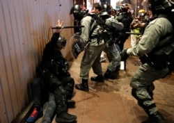 FILE - Riot police detain a protester, left lying on the ground, during a demonstration in Hong Kong, Dec. 25, 2019.