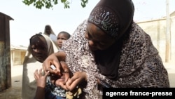 FILE - A health worker tries to immunize a child during a vaccination campaign against polio at Hotoro-Kudu, Nassarawa district of Kano, in northwest Nigeria, April 22, 2017. 