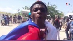 A protester holds a Russian flag saying Haiti is unfriending the US. (VOA/S. Lemaire)