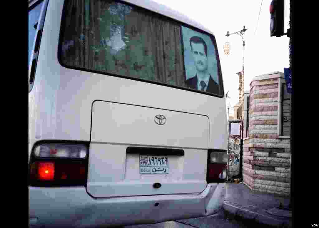 A poster of Syrian president Bashar al-Assad hangs in the rear window of a bus in Damascus. (J. Weeks/VOA)