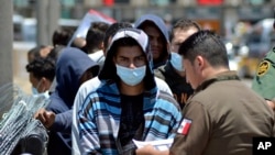 FILE - Mexican officials and U.S. Border Patrol officers return a group of migrants to the Mexico side of the border as Mexican immigration officials check the list, in Nuevo Laredo, Mexico, July 25, 2019. 