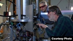 NIST physicists Steve Jefferts (foreground) and Tom Heavner with the NIST-F2 “cesium fountain” atomic clock, a new civilian time standard for the United States.