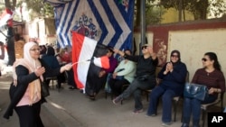 Voters sing national songs as they prepare to enter a polling station during the first day of the presidential election in Cairo, March 26, 2018. 