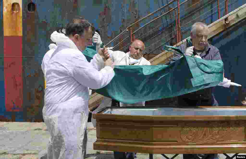 People carry the body of a dead migrant from a merchant ship as they arrive in the Sicilian harbor of Catania, southern Italy, May 5, 2015.&nbsp;