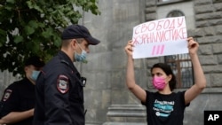 Police detain a journalist with the poster reads "Journalism Freedom", during individual pickets in Moscow, Russia, Aug. 21, 2021. 