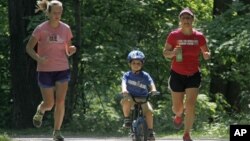 In this 2012 file photo, Andrea Lemastra, right, and Kim Walsh, left, jog on a wooded park trail with Lemastra's four-year-old son, Luca, in the U.S. state of Ohio. (AP Photo/Mark Duncan)