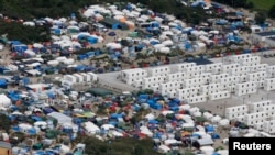 FILE - A makeshift camp of shipping containers and tents houses migrants in the 'jungle,' a sprawling camp at the French port of Calais. Two camps planned in Paris could lead to its dismantling.
