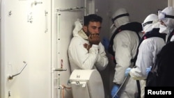 A surviving immigrant, left, arrives by Italian coast guard ship Bruno Gregoretti at the harbor in Catania, Italy, April 20, 2015. 