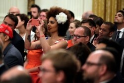 Invited guests take photos as President Donald Trump speaks during the Social Media Summit in the East Room of the White House, July 11, 2019.