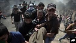 Palestinian protesters carry an injured man who was shot by Israeli troops during a protest at the Gaza Strip's border with Israel, May 14, 2018.
