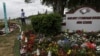 FILE - Chad Williams, 19, a survivor of the Marjory Stoneman Douglas High School shooting, stands alone at a memorial garden outside the school in Parkland, Fla., March 16, 2019.
