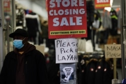 FILE - Sale signs are displayed in the window of a business in Brooklyn in New York City, Dec. 1, 2020.