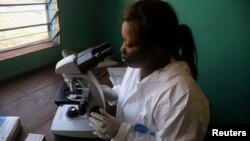 FILE - A laboratory worker uses a microscope at the health center in the commune of Wangata during a vaccination campaign against the outbreak of Ebola, in Mbandaka, Democratic Republic of the Congo, May 23, 2018. 