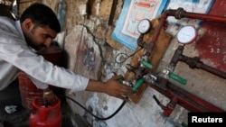 A man gauges liquefied petroleum gas in a cylinder at his makeshift shop in Karachi on April 22, 2010. Pakistan is battling a chronic energy shortage, stifling industry and angering the public. 
