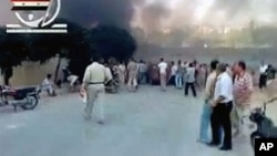 People gather in a street in Hama as smoke rises in the background in this video image posted on a social media website on August 2, 2011 (the authenticity of the video from which this image was taken cannot be independently verified)