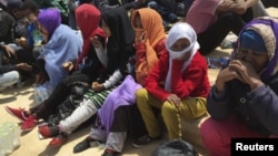 FILE - Migrants who attempted to sail to Europe sit on the shore after their boat was intercepted at sea by the Libyan coast guard in Khoms, Libya, May 6, 2015.