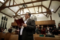 Baptist Pastor Clifford Maung, front, an immigrant from Myanmar, also known as Burma, sings a hymn with members of his congregation at the Overseas Burmese Christian Fellowship in Boston, Feb. 16, 2020.