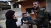A woman asks a Free Syrian Army fighter to sell her bread, in Maaret Misreen, near Idlib, Syria, December 13, 2012.