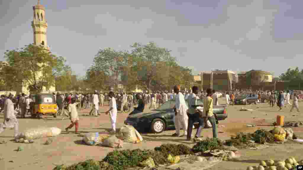 Mutane sun taru su na kallo a inda bam ya tashi a babban Masallacin Jumma'a na Kano, Jumma'a 28 Nuwamba, 2014. Mutane da yawa sun rasa rayukansu, kuma jami'ai suka ce watakila yawan wadanda zasu hallaka zai karu.