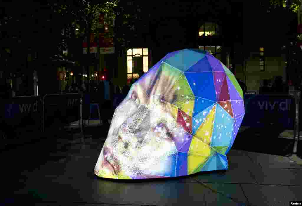 Wajah seorang perempuan diproyeksikan langsung pada sebuah patung seni berbentuk kepala pada acara festival musik dan cahaya di Sydney, Australia.