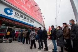 Customers lining up to have their temperature taken before entering the bank in Nantong, China, Feb. 25, 2020. The bank was controlling the number of people inside the bank at any one time as a precaution against the COVID-10 coronavirus.
