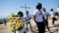 FILE - Youths of Cite Soleil carry flowers and a cross to a monument honoring the victims of the 2010 earthquake before a memorial service at Titanyen, a mass burial site north of Port-au-Prince, Haiti, Jan. 12, 2019.