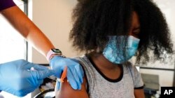 FILE - Jackson State University student Kendra Daye reacts as Tameiki Lee, a nurse with the Jackson-Hinds Comprehensive Health Center, injects her with the Pfizer COVID-19 vaccine, in Jackson, Miss., Sept. 21, 2021.