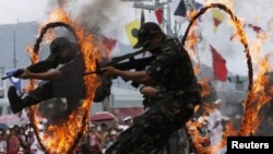 FILE - Chinese People's Liberation Army (PLA) soldiers jump through rings of fire in a war game as part of the show for the public during an open day at the Ngong Shuen Chau Naval Base on Hong Kong's Stonecutters Island, July 28, 2012.