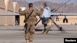 A US airman guides a US Air Force MQ-9 Reaper drone as it taxis to the runway at Kandahar Airfield, Afghanistan, March 9, 2016. 