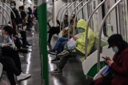 People wearing face masks travel in the subway in Wuhan, in China's central Hubei province, April 13, 2020.