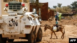 Seorang anak laki-laki Sudan menunggang keledai melintas di depan kendaraan Misi PBB-Uni Afrika (UNAMID) di Kota Golo yang dikoyak peran di wilayah Jebel Marra di Darfur tengah, 19 Juni 2017.

