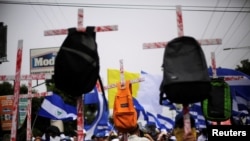 FILE - Demonstrators hold up crosses with backpacks during a march to demand the resignation of Nicaragua's President Daniel Ortega in Managua, Nicaragua, July 23, 2018.