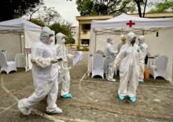 Health workers walk through the grounds at a makeshift COVID-19 testing facility in Hanoi, Vietnam, March 31, 2020.