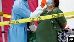 Jerry A. Mann, center, watches as his grandmother, Sylvia Rubio, is tested for COVID-19 by the San Antonio Fire Department at a free walk-up test site set up to help underserved and minority communities in San Antonio, Texas, May 14, 2020. 