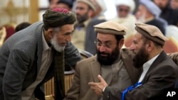 Afghanistan's former Prime Minister Ahmad Shah Ahamdzai, right, talks with an Afghan delegate as Ghairat Baheer, center, head of political cell Hizb-e-Islami Afghanistan listens during a conference title 'Peace and Reconciliation in Afghanistan', in Islamabad, Pakistan, Jan. 28, 2014.