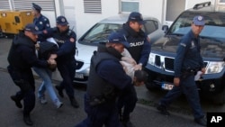 Montenegrin police officers escort men for questioning, in Podgorica, Montenegro, Oct. 16, 2016, as the small Balkan country held parliamentary elections.