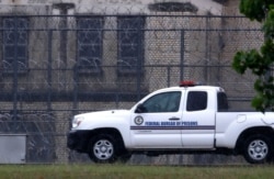 FILE - A Federal Bureau of Federal Prisons truck drives past barbed wire fences at the Federal Medical Center prison in Fort Worth, Texas, May 16, 2020. Hundreds of inmates inside the facility have tested positive for COVID-19.