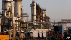FILE - In this Sept. 20, 2019, file photo, taken during a trip organized by Saudi information ministry, workers fix the damage in Aramco's oil separator at processing facility after the recent Sept. 14 attack in Abqaiq, near Dammam in the Kingdom's…