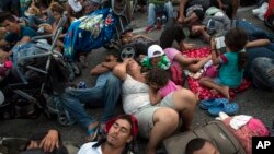 Members of a US-bound migrant caravan rest on a road between the Mexican states of Chiapas and Oaxaca after federal police briefly blocked them outside the town of Arriaga, Oct. 27, 2018. 